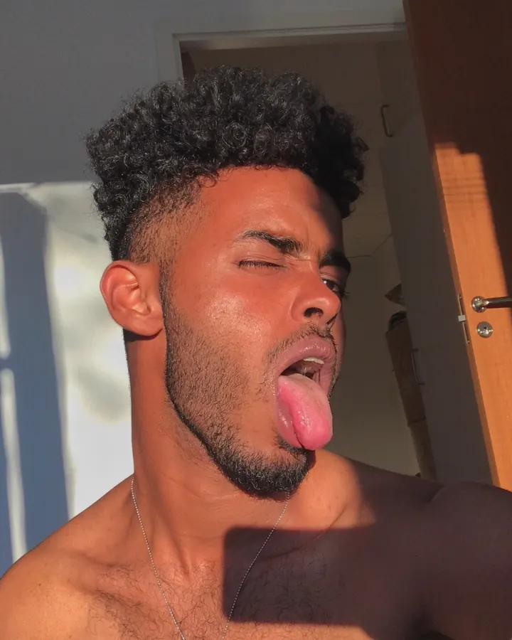 Homme torse nu, regardant l'appareil photo, bras levés, en extérieur.