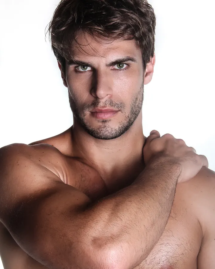 Homme torse nu, regardant l'appareil photo, main sur le ventre, en extérieur.