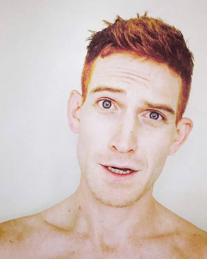 Homme aux cheveux roux, torse nu, regardant directement l'appareil photo