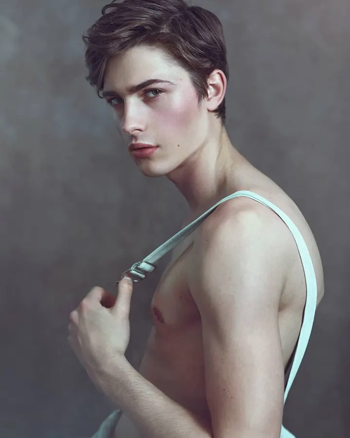 Homme blanc, torse nu, portant un slip, posant devant un arbre.