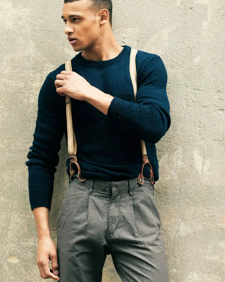 Homme barbu, cheveux blonds, torse nu, regard direct, en extérieur.