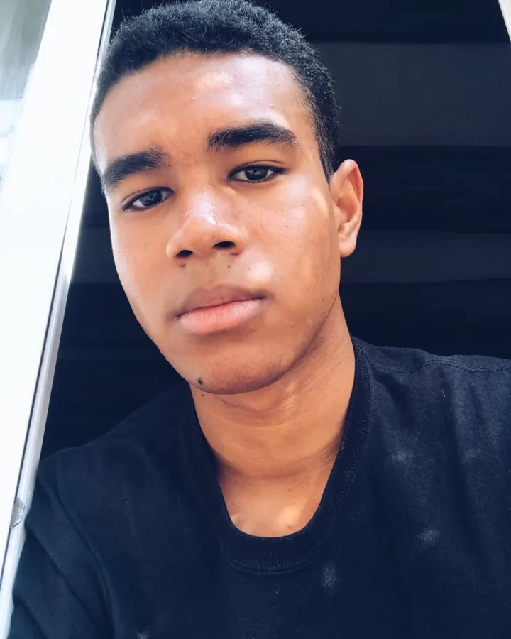 Jeune homme en t-shirt noir, regard direct, photo en gros plan, en extérieur.
