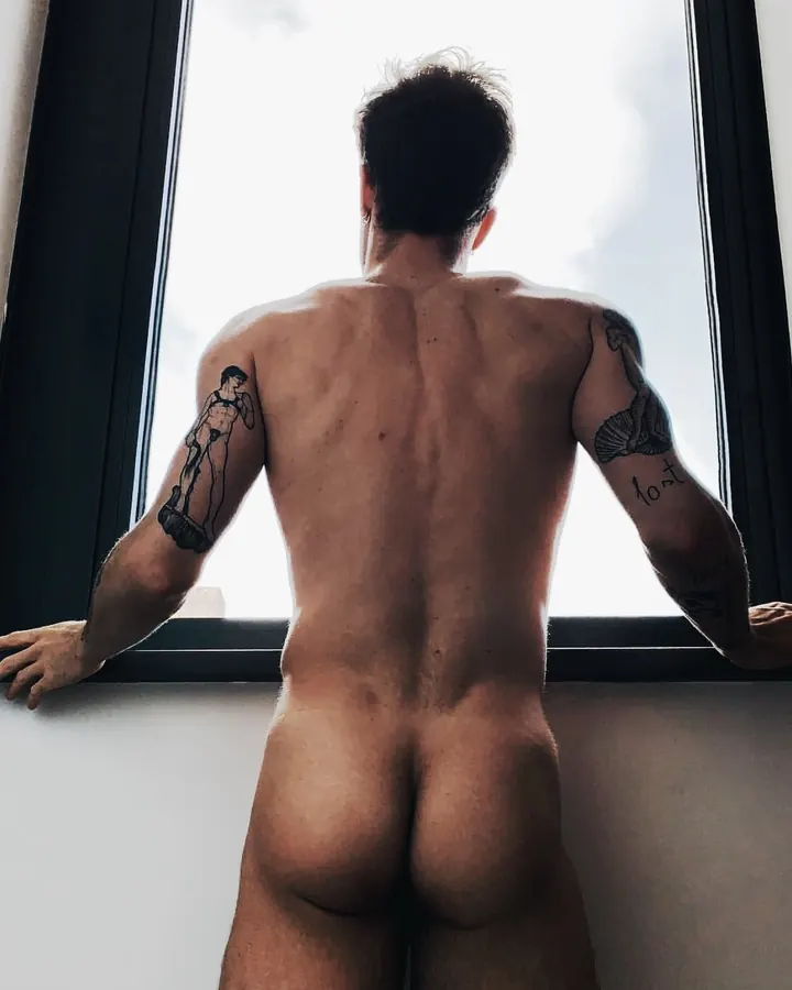 Homme torse nu, sous-vêtements noirs, dans une douche, regard vers le côté.
