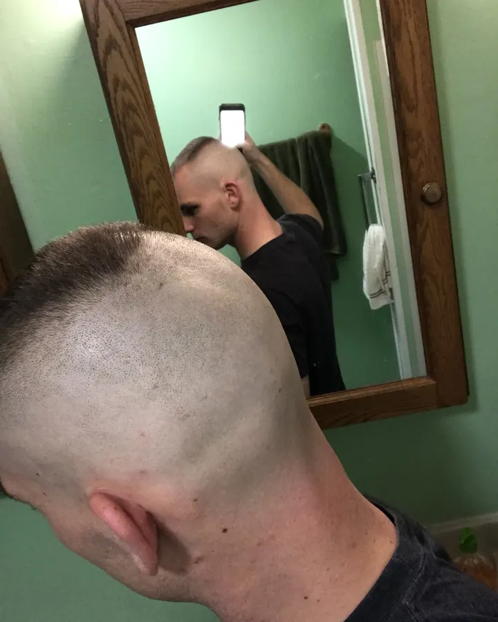 Homme torse nu, coiffure rasée, photo en miroir, salle de bain verte.