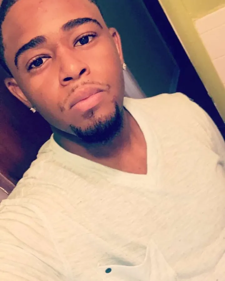Homme torse nu, cheveux bruns, regardant directement l'objectif, dans un cadre sombre