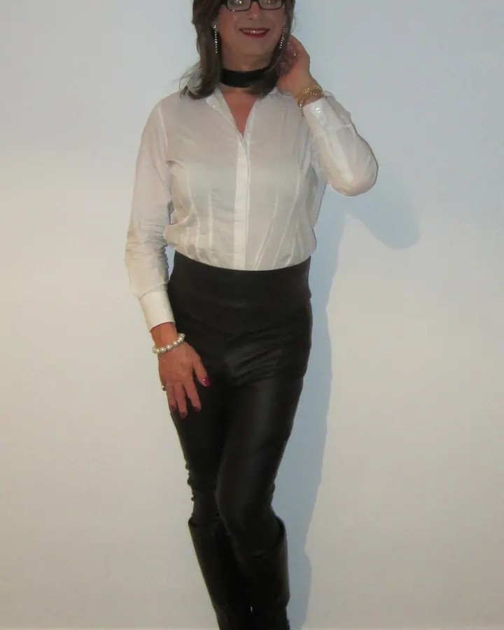 Femme aux cheveux blonds, portant un haut noir, regardant l'appareil avec un regard intense et un léger sourire.